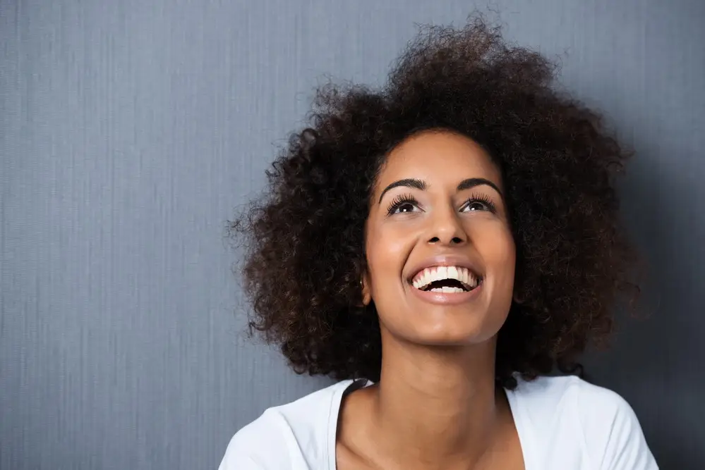 Smiling woman looking upward with hope, reflecting recovery and renewal in addiction treatment.