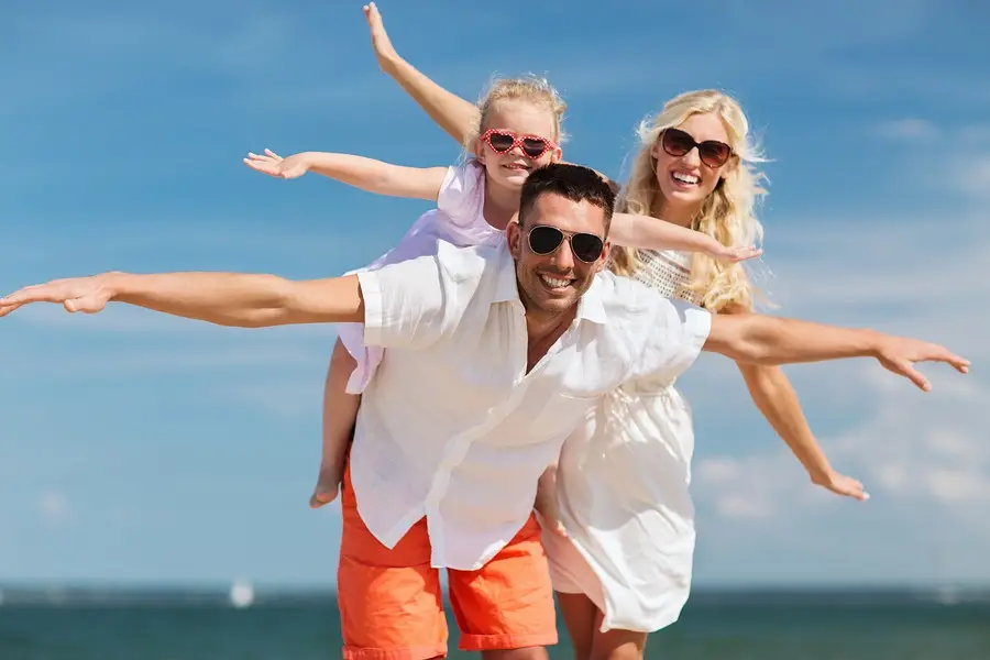 Happy family smiling on a sunny beach, enjoying time together in recovery and renewed health.